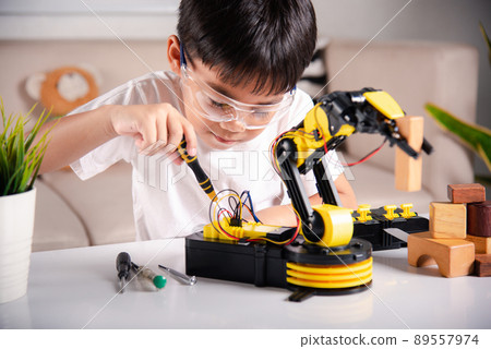 Happy Asian little kid boy using screwdriver to fixes screws robotic machine arm in home workshop Happy Asian little kid boy using screwdriver to fixes screws robotic machine arm in home workshop 89557974