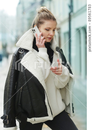 young blond slavic woman with cell phone in black leather jacket closeup street portrait young blond slavic woman with cell phone in black leather jacket closeup street portrait 89561783