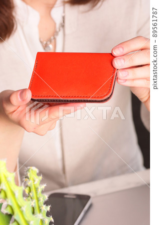 red leather cardholder in woman hands closeup photo on white wall background red leather cardholder in woman hands closeup photo on white wall background 89561787