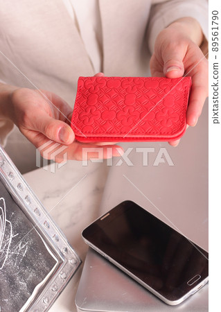 red leather cardholder in woman hands closeup photo on white wall background red leather cardholder in woman hands closeup photo on white wall background 89561790