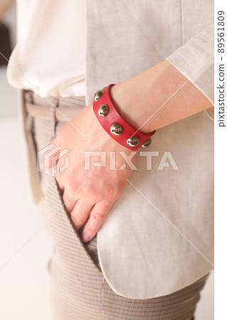 leather studded red bracelet on woman hand closeup photo on white wall background leather studded red bracelet on woman hand closeup photo on white wall background 89561809