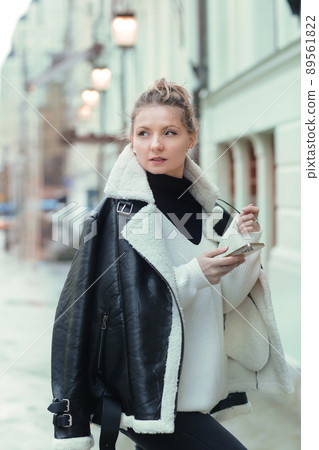 young blond slavic woman with cell phone in black leather jacket closeup street portrait young blond slavic woman with cell phone in black leather jacket closeup street portrait 89561822