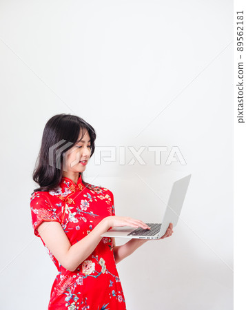 Portrait of a young asian woman in traditional cheongsam qipao dress using laptop on white background. Portrait of a young asian woman in traditional cheongsam qipao dress using laptop on white background. 89562181