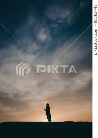 Female silhouette and beautiful sunset sky Female silhouette and beautiful sunset sky 89562448