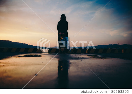 Silhouette of a woman holding an umbrella and a beautiful sunset sky 89563205