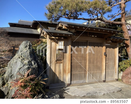 它是一棟純日式房屋的大門,松樹和花園石頭。 它是一棟純日式房屋的大門,松樹和花園石頭。 89563507