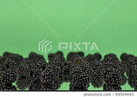 Blackberry fruit on light green mirror. Side view. Selective focus. Blackberry fruit on light green mirror. Side view. Selective focus. 89564093