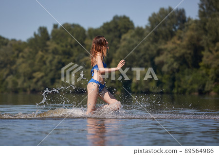 Girl at the beach running into the water Girl at the beach running into the water 89564986