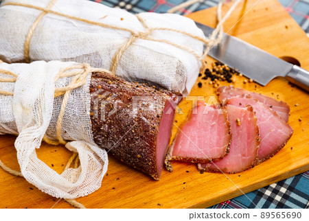 Spicy dry-cured pork fillet with sliced pieces on wooden board 89565690