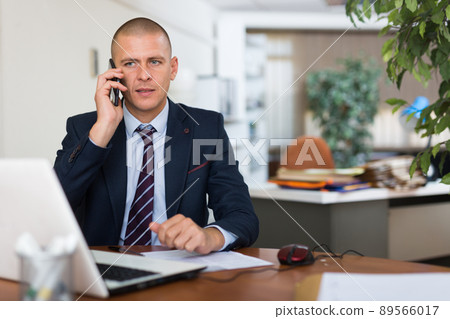 Male clerical worker having telephone conversation Male clerical worker having telephone conversation 89566017