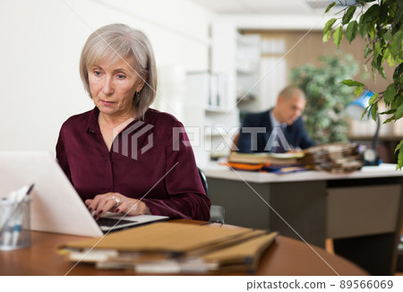 Busy focused aged female entrepreneur working with papers and laptop 89566069