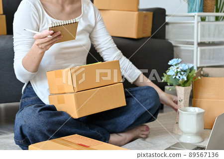 Cropped image, Female online shop owner packing her product into a parcel box 89567136