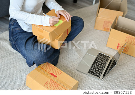 Female SME business entrepreneur packing the parcel boxes at home. Female SME business entrepreneur packing the parcel boxes at home. 89567138