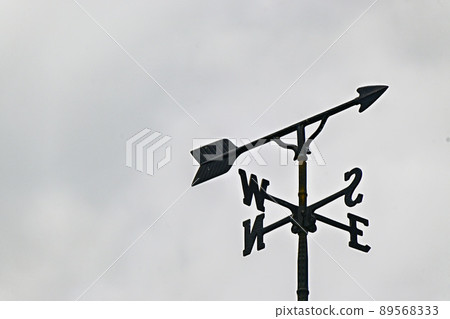 Looking up at the weathercock pointing in the direction under cloudy weather, north, south, east and west 89568333