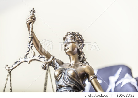 The statue of justice Themis or Iustitia, the goddess of justice blindfolded against a flag of the United States of America, as a legal concept. 89568352