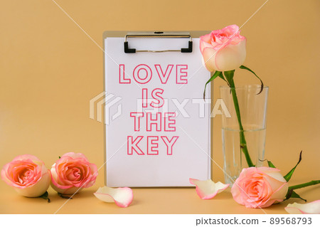 LOVE IS THE KEY text on greeting card paper note. Delicate pink roses on beige background. Minimal trendy composition. Romantic pastel pink rose flowers. Neutral earth tones. Preparation for LOVE IS THE KEY text on greeting card paper note. Delicate pink roses on beige background. Minimal trendy composition. Romantic pastel pink rose flowers. Neutral earth tones. Preparation for 89568793