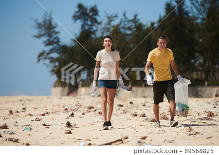 Couple Picking up Trash on Beach Couple Picking up Trash on Beach 89568825