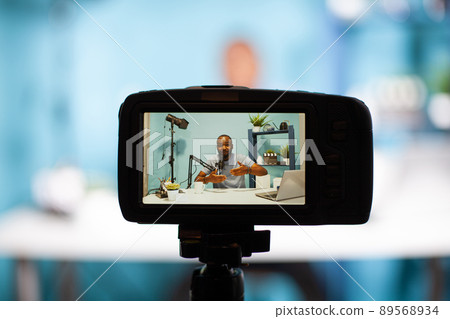 Selective focus on back screen of dslr filming social media influencer hosting live talk in vlogging studio. Closeup of professional digital camera recording content creator talking in live podcast. Selective focus on back screen of dslr filming social media influencer hosting live talk in vlogging studio. Closeup of professional digital camera recording content creator talking in live podcast. 89568934