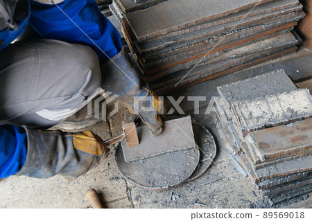Worker in heavy industry or metallurgy beats scale off iron plates with hammer. Work with metal Worker in heavy industry or metallurgy beats scale off iron plates with hammer. Work with metal 89569018