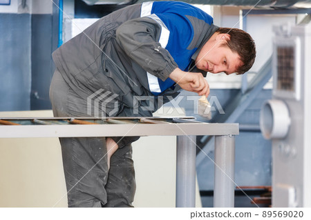 Painter of 30-40 years of Caucasian appearance paints metal structure in production hall with paint Painter of 30-40 years of Caucasian appearance paints metal structure in production hall with paint 89569020