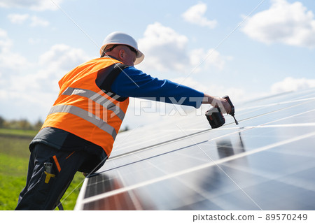 Man with drill screwdriver installs panels at a solar power plant Man with drill screwdriver installs panels at a solar power plant 89570249