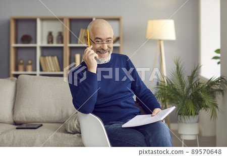 Portrait of positive elderly man who likes to write down ideas in his notebook at home. 89570648