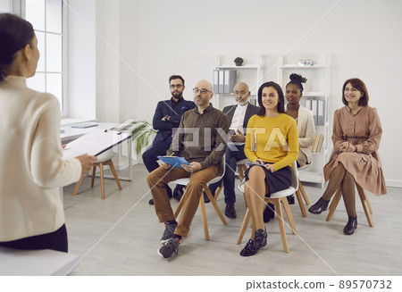 Group of business people at consultation meeting listens to report of their female colleague. Group of business people at consultation meeting listens to report of their female colleague. 89570732