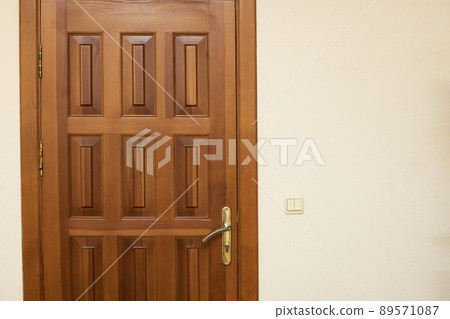 Wooden door on white wall close up Wooden door on white wall close up 89571087
