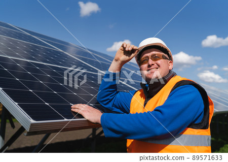 Portrait of a solar farm worker leaning against the panels 89571633