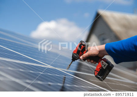 Close-up of engineer's hand with a drill screwdriver repairing a solar panel Close-up of engineer's hand with a drill screwdriver repairing a solar panel 89571911