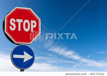 Stop and One Way Road Sign against a Clear Blue Sky and Clouds 89572262