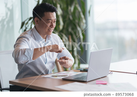 Asian businessman communicating in video call with deaf client at her workplace 89573068