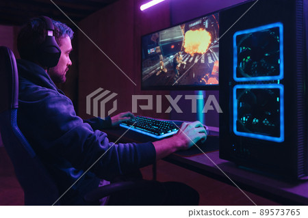 Pro gamer splaying multiplayer computer video game in dark neon room Pro gamer splaying multiplayer computer video game in dark neon room 89573765