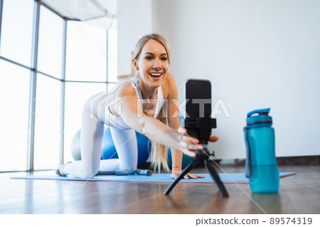 Joyful female fitness blogger setting up her smartphone before starting streaming 89574319