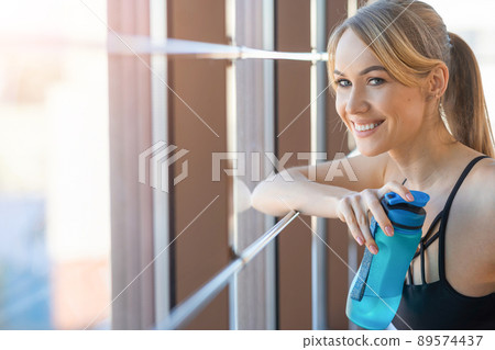 Portrait of beautiful fitness woman with sports bottle in her hand 89574437