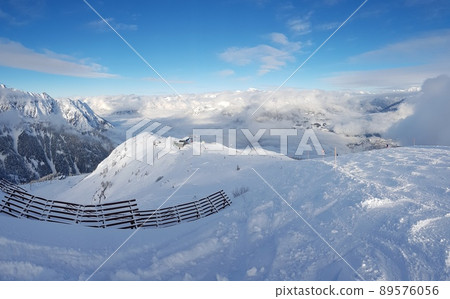Panoramic view over snowy ski resort in Austrian Alps during daytime with sunshine and clouds Panoramic view over snowy ski resort in Austrian Alps during daytime with sunshine and clouds 89576056