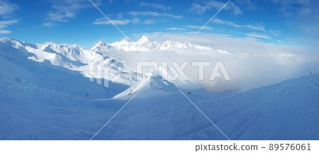 Panoramic view over snowy ski resort in Austrian Alps during daytime with sunshine and clouds 89576061