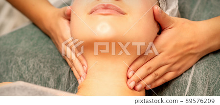 Facial massage. Hands of a masseur massaging neck of a young caucasian woman in a spa salon, the concept of health massage Facial massage. Hands of a masseur massaging neck of a young caucasian woman in a spa salon, the concept of health massage 89576209
