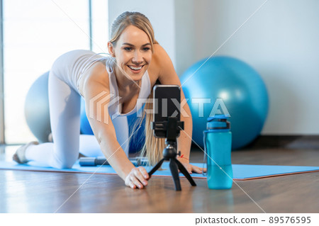 Sports female fitness blogger smiling at smartphone camera Sports female fitness blogger smiling at smartphone camera 89576595
