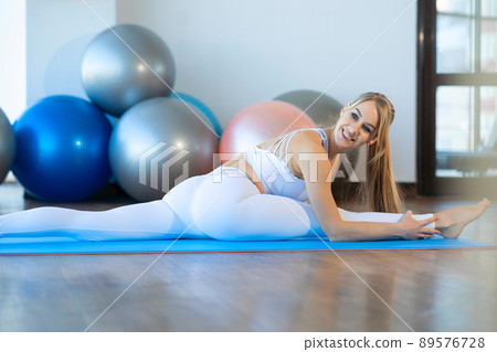Pretty girl doing twine on yoga mat. .Flexible girl stretching indoors 89576728