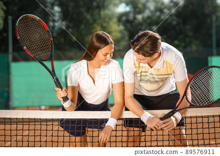 Young couple talking after playing tennis Young couple talking after playing tennis 89576911