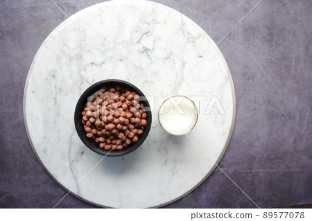 Top view of chocolate corn flakes in a bowl and glass of milk on table Top view of chocolate corn flakes in a bowl and glass of milk on table 89577078