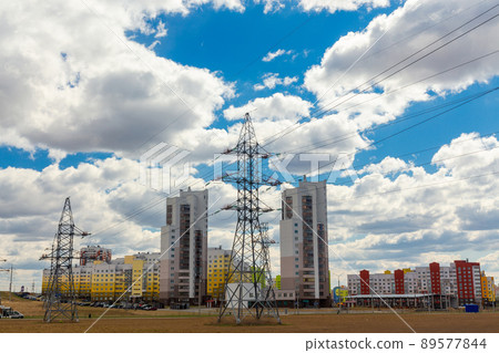 Power lines in the city near residential buildings against a blue sky. 89577844