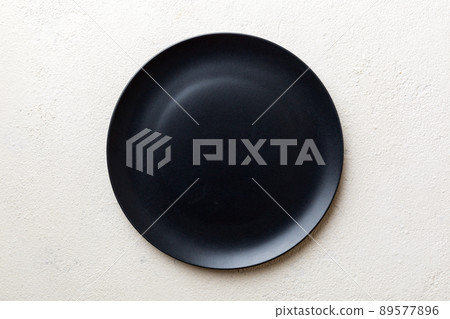 Top view of black plate on cement background. Empty space for your design 89577896