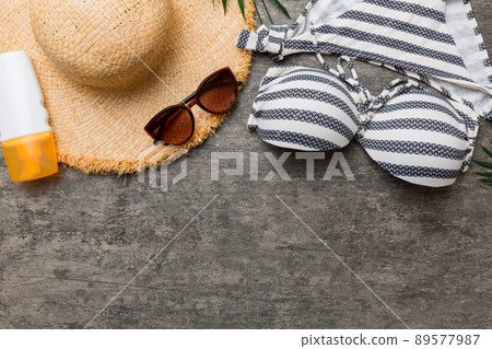 Woman swimwear and beach accessories flat lay top view on colored background Summer travel concept. bikini swimsuit, straw hat and seasheels. Copy space Top view 89577987