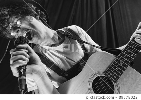 Repetition of retro music band at music studio. Young musician playing acoustic guitar and singing. Rehearsal base. Concept of art, music, style and creation Repetition of retro music band at music studio. Young musician playing acoustic guitar and singing. Rehearsal base. Concept of art, music, style and creation 89578022