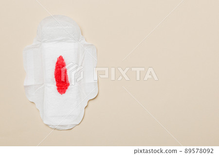 Women hygiene products or Sanitary pad with red feather on colored background. Pastel color. Closeup. Empty place for text. Female daily hygiene 89578092