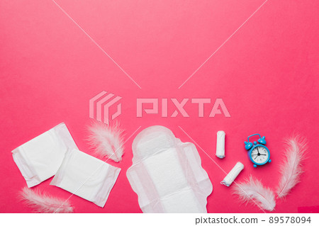 Ringing alarm clock with sanitary female tampons and menstrual sanitary pads. Medical concept of woman critical days and menstruation. Female daily hygiene. Copy space Ringing alarm clock with sanitary female tampons and menstrual sanitary pads. Medical concept of woman critical days and menstruation. Female daily hygiene. Copy space 89578094