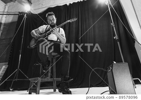 Repetition of retro music band at music studio. Young musician playing electric guitar and singing. Rehearsal base. Concept of art, music, style and creation 89578096