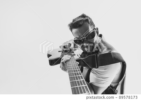 Solo performance Black and white portrait of stylish rock musician with electric guitar isolated on white background. Concept of art, music, style Solo performance Black and white portrait of stylish rock musician with electric guitar isolated on white background. Concept of art, music, style 89578173